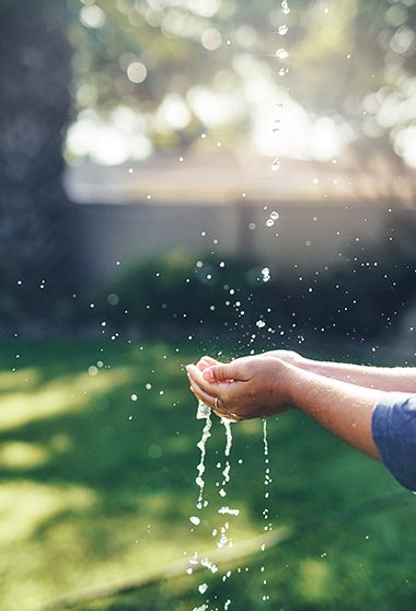 dans un habitati naturel et tenant ses mains pour attraper des gouttes d’eau